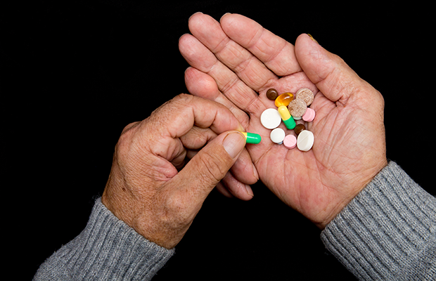Aerial photograph of elderly person holding some pills.