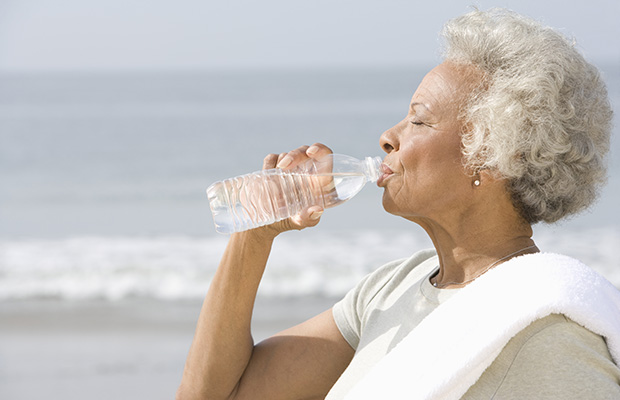 Elderly woman drinking water on the beach