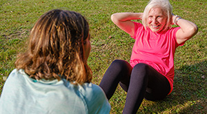 Elderly woman doing abdominal crunches in the park