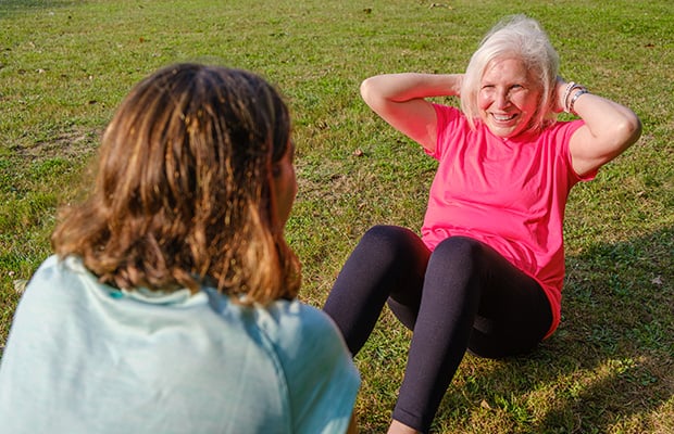 Elderly woman doing abdominal crunches in the park