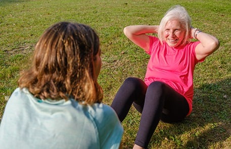 Elderly woman doing abdominal crunches in the park
