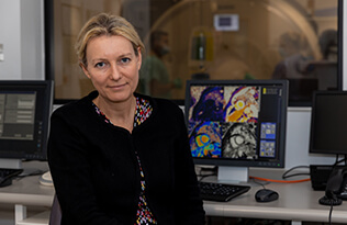 Charlotte Manisty sits in front of a computer screen of MRI scan images