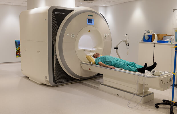 An adult lying down on an MRI scanner table.