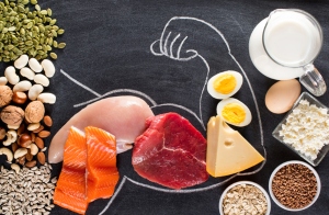 A chalk outline of a flexing bicep filled with high-protein foods like meat, fish, nuts, cheese and eggs.