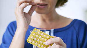 Woman taking an HRT tablet during menopause