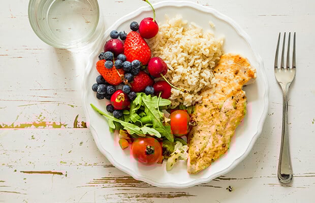 Plate of rice, salad, berries and a white fish fillet
