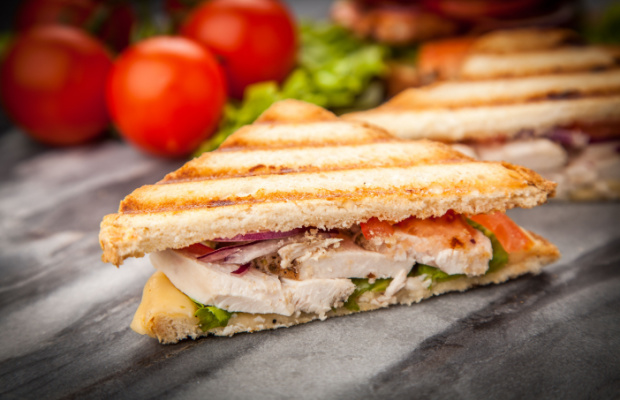 A white bread toastie sandwich filled with chicken, tomato, onion and cheese.