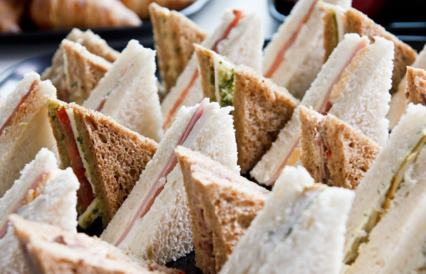 A platter of triangular white and brown bread sandwiches with the crusts cut off