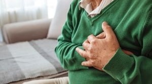 Man sits on a sofa with his hands on his chest.
