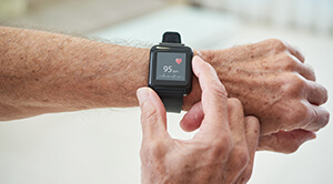 A square black heart rate monitor watch worn on a person's wrist showing 96bpm on the screen