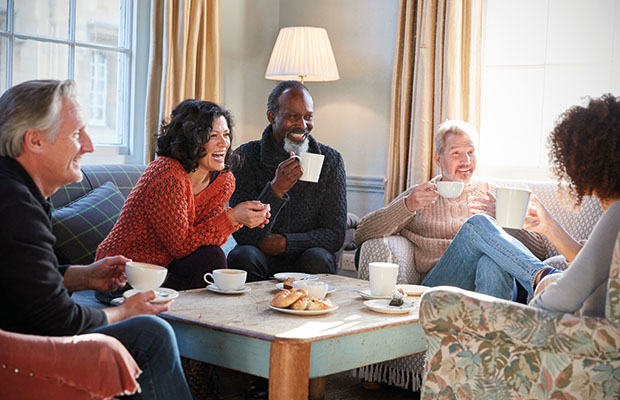 A diverse group of middle-aged adults sitting around a coffee table having conversation.