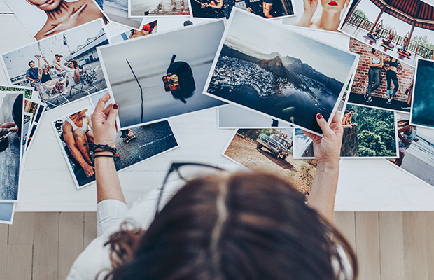 A person chooses between two landscape photographs while making a collage.