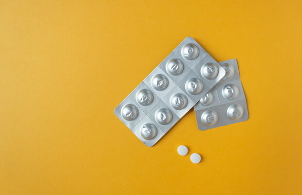Two silver blister packs of pills with two white round tablets