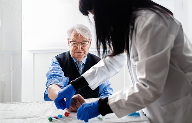 A healthcare professional picks up a bottle for a man having a blood test.