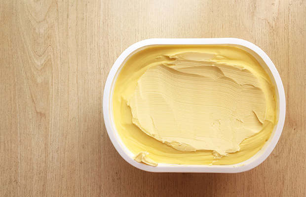 An aerial view of an open tub of margarine on a table.