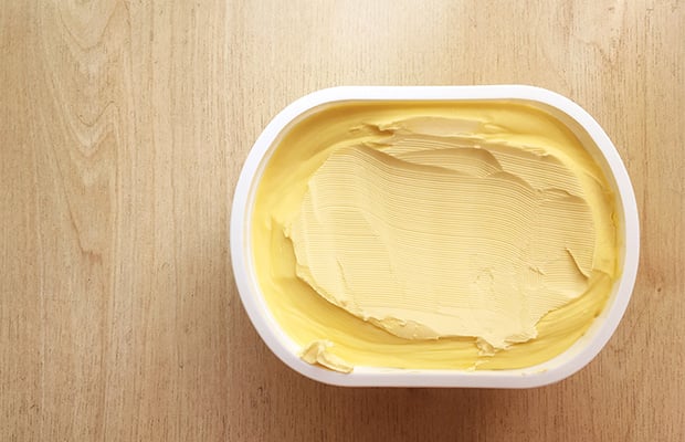 An aerial view of an open tub of margarine on a table.