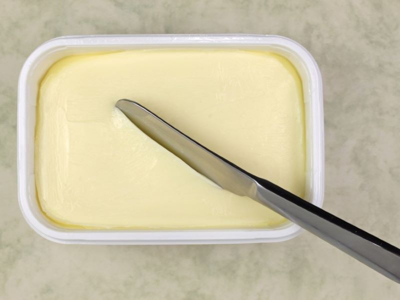 An aerial view of an open tub of margarine on a table.