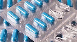 A close-up of a pile of packets of blue pills.