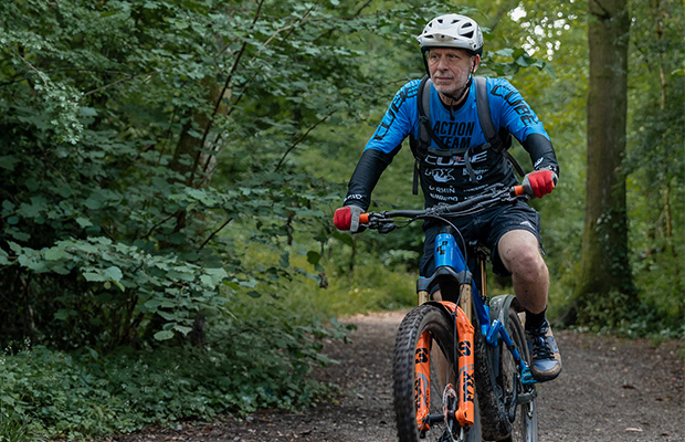 Neil riding his e-bike on a path in a forest.