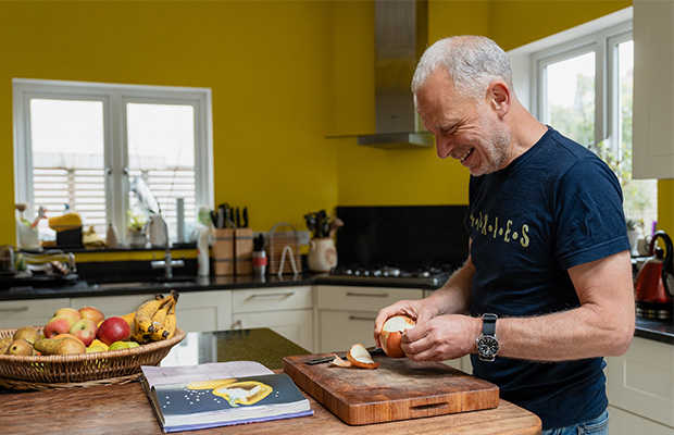 Neil peeling an onion in his kitchen.