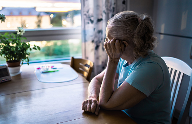 A woman sits inside at a table and looks out the window.