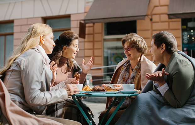 A group of woman chatting over coffee and pastries.