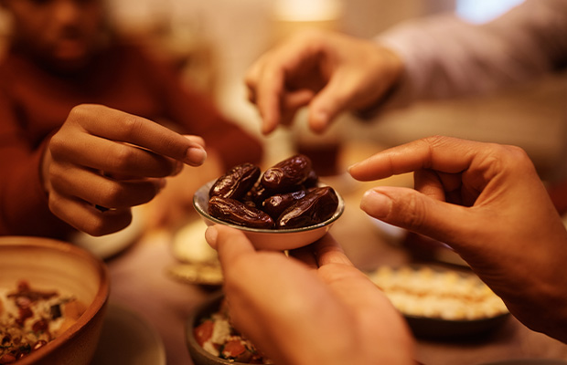 Close up of Muslim family eating dates during Iftar meal at dining table.