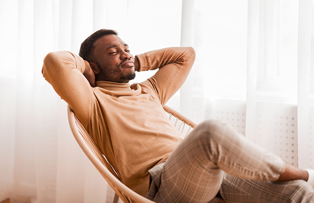 A person dozing happily on a comfortable-looking chair.