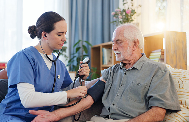 A nurse checks a man's blood pressure at home.