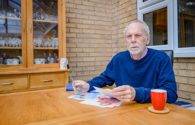 Glynn Evans sits at a table looking at photographs, at his home.