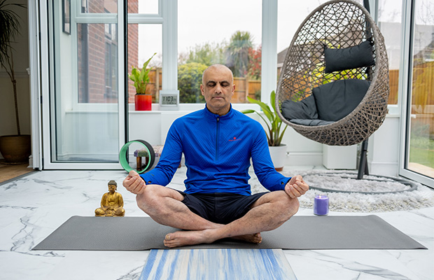 Sad sat cross legged with his eyes closed on a yoga mat