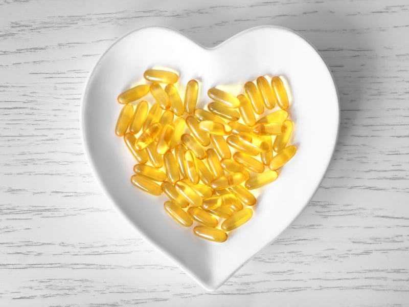 Yellow capsules in white heart shaped bowl