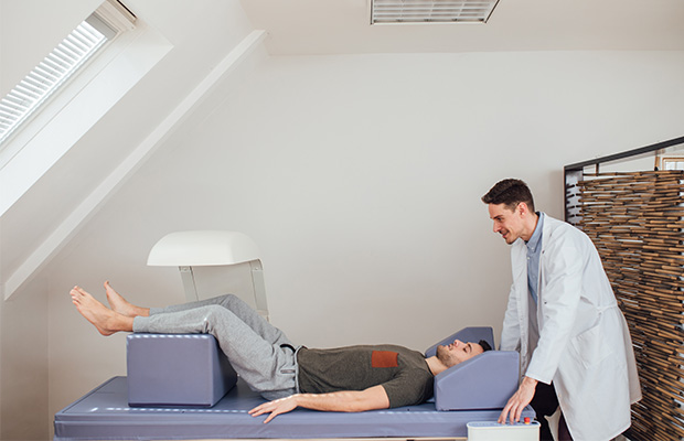A doctor operates a scanning arm over a man lying on a table