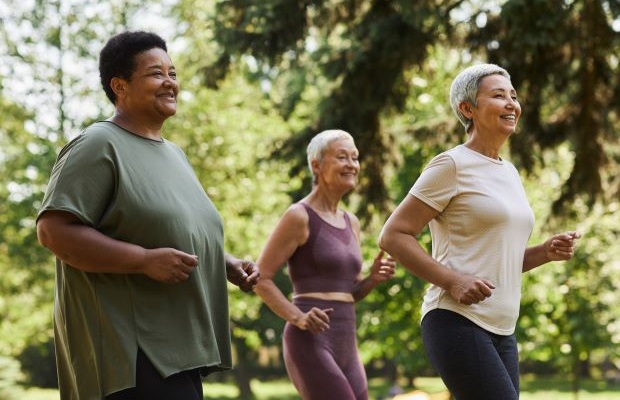 Three women running in a park on a sunny day.