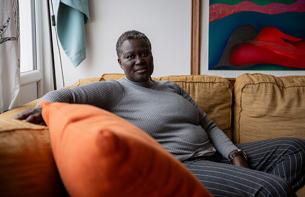 Alice Odeke sits on her sofa