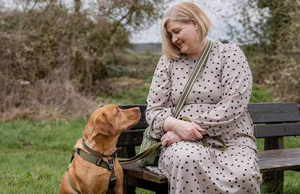 Gini Dellow sitting on a bench outside looking at her dog