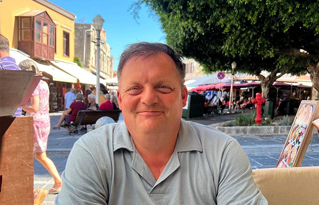 Andy sits outside at a restaurant in Greece