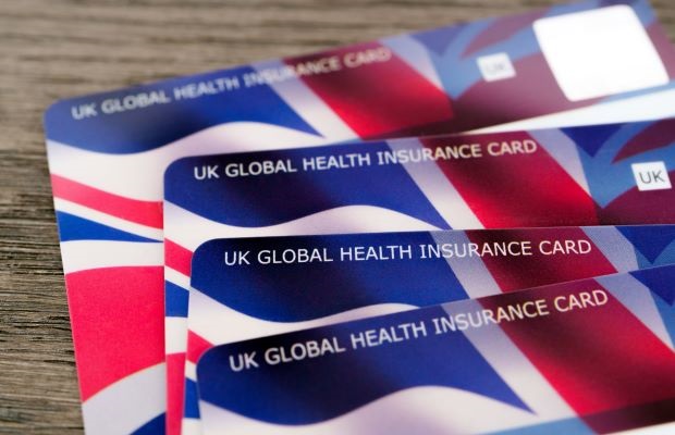 A set of four Global Health Insurance Cards arranged on a wooden background.
