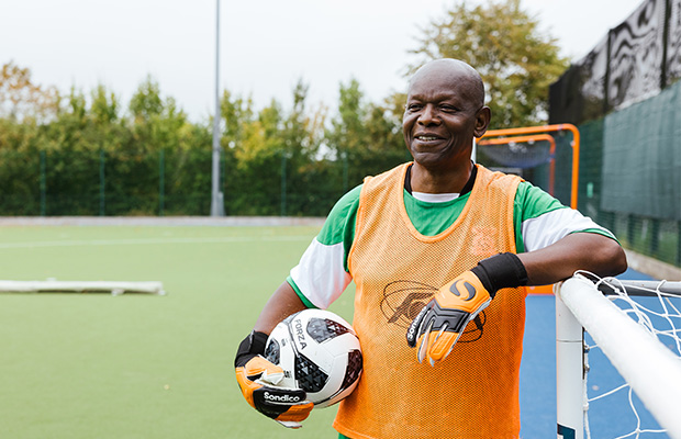Chella Chilombo Sikazwe standing on a football pitch holding a football.
