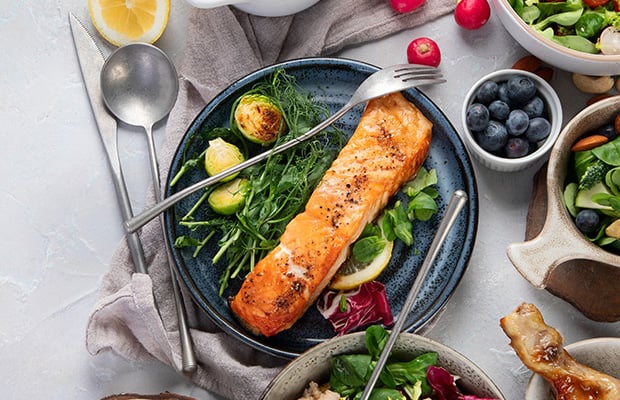 A plate of salmon on a table with other foods.