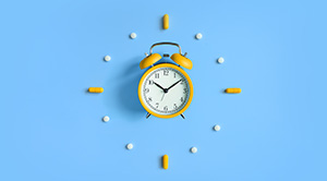 A clock surrounded by medicine tablets.