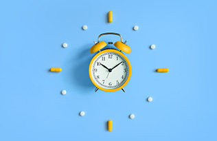 A clock surrounded by medicine tablets.