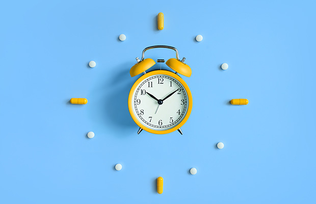 A clock surrounded by medicine tablets.