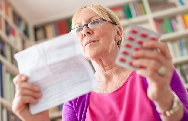 A woman reading the leaflet of a medicine.