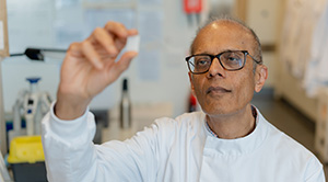 Professor Ajay Shah looking at a slide in a lab.