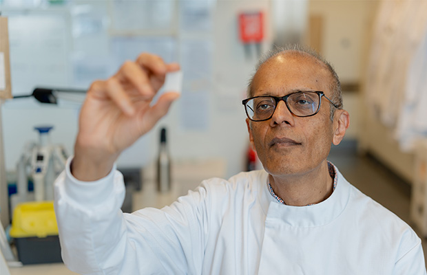 Professor Ajay Shah looking at a slide in a lab.