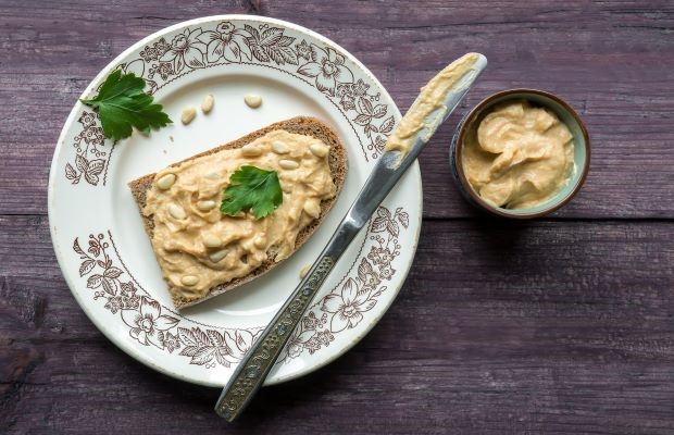 Arial view of toast with hummus spread on top, and a small bowl of hummus next to it.