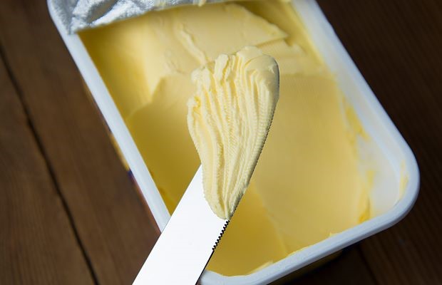 Close up arial view of an open pack of margarine with knife resting on top.