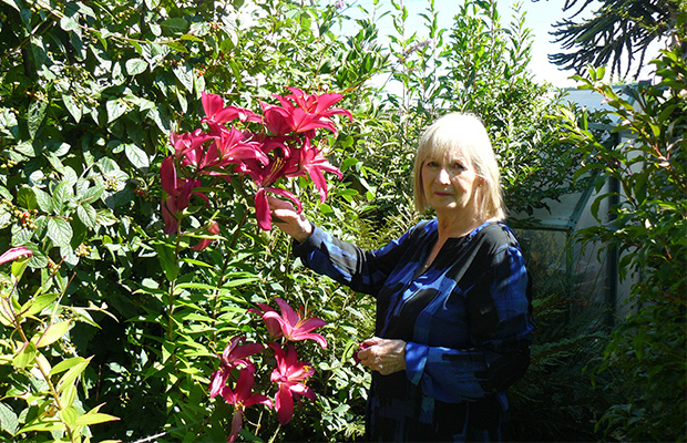 Marian Sedgwick standing by flowers in her garden.