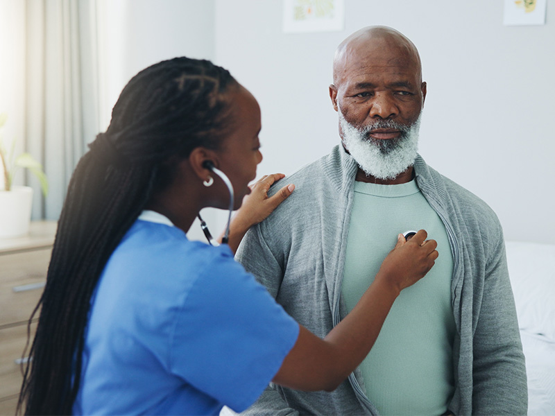 A doctor listening to a man's chest with a stethoscope. 